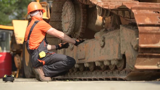 Heavy Duty Equipment Mechanic Side by Side with Aged Bulldozer. Industrial Concept.