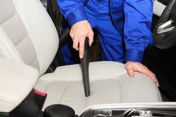 Closeup of worker vacuuming automobile seat, view from inside. Car wash service