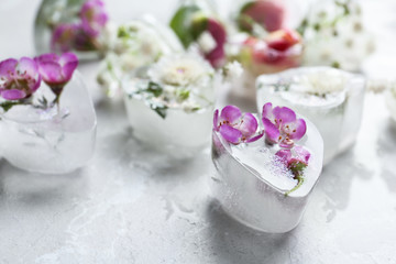 Heart shaped ice cubes with flowers on grey background, closeup. Space for text