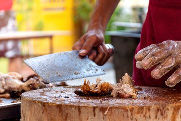 The chef is using a knife to cut the barbecued suckling pig