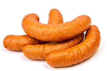 Sausages on a light background. Juicy sausage rings in a pile on a white background.