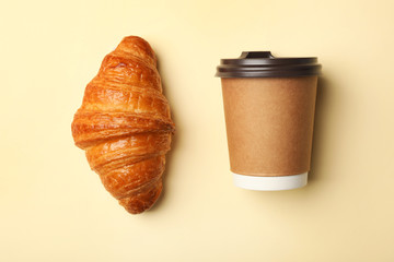 Paper coffee cup and croissant on color background, flat lay. Mockup for design