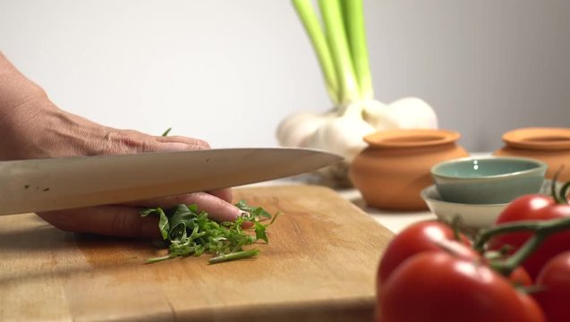 Cutting green rucola on the wooden board side view