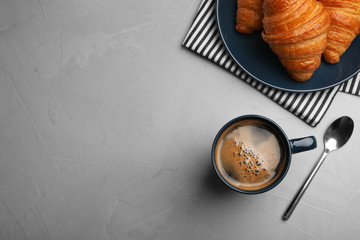 Flat lay composition with coffee and croissants on grey table, space for text