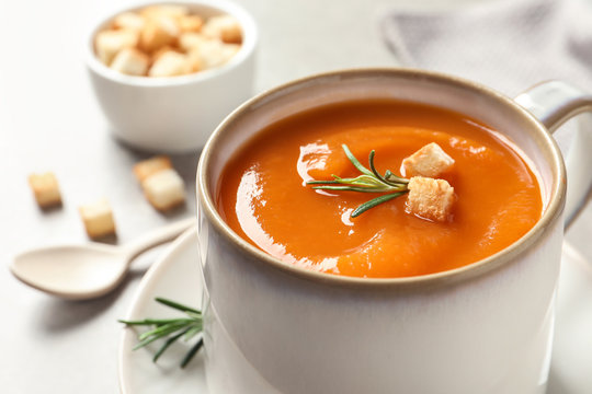 Mug of tasty sweet potato soup on table, closeup