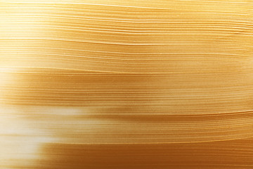 Strokes of gold paint as background, top view