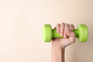 Woman holding vinyl dumbbell on color background, closeup with space for text