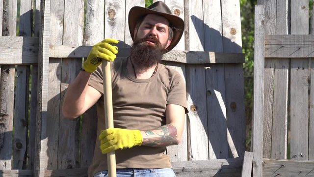 Man with beard - farm worker. Garden tools. Farmer watering the sprout on field. Earth day. Emotional funny bearded hipster on the farm.
