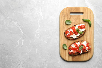 Board with tasty bruschettas on grey table, top view. Space for text