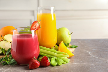 Glasses with different juices and fresh fruits on table against blurred background. Space for text