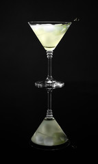 Glass of delicious cucumber martini with ice on dark background
