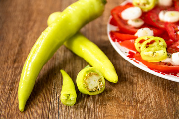 Salad with fresh tomatoes, young onion and hot paprika on wooden table