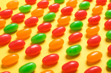 Delicious bright jelly beans on color background