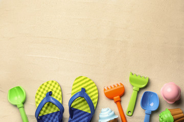 Flat lay composition with beach toys on sand. Space for text