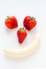the face of a man made of three strawberries and a peeled banana