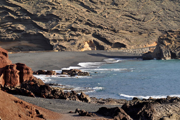 Striking view of El Golfo bay: red ground, blue ocean and black sand with volcanic mountains on background, Lanzarote, Canary Islands