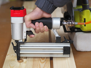 Air Nailer, Stapler pneumatic work with hand controls. Carpenter fix clapboard