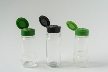 3 Multiple reusable spice seasoning jars; Green & black sprinkle lid tops for recycling campaign programs; Isolated kitchen item on horizontal white background
