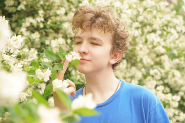 young man stands among the flowers and enjoys summer and flowering