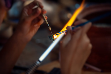 Glass artisan making a glass butterfly decoration stuff with propane torch