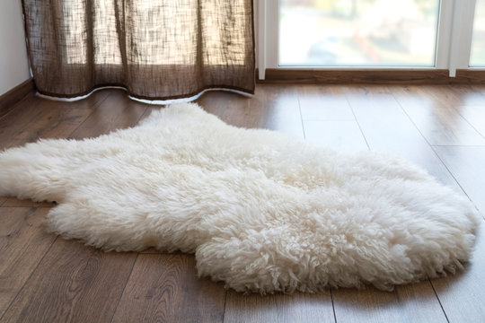 Sheep skin on the laminate floor in the room. Cozy place near the window.