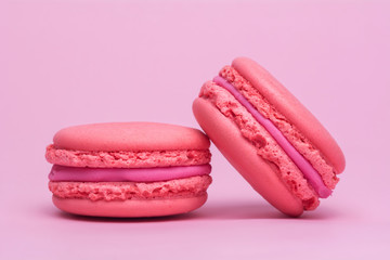 Two pink macaron cookies on a pink background
