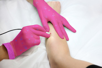 Women's hand in unusual gloves when removing hair with an electric hair removal device