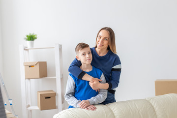 Positive smiling mother and charming son are posing standing in a new bright comfortable apartment. The concept of moving and mortgages for new housing.