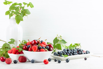 Berries closeup colorful assorted mix of strawberry, blueberry, raspberry and sweet cherry on a white table.
