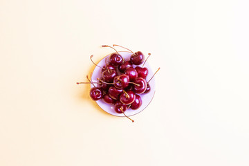 Ripe fresh sweet cherry on pastel yellow. The concept of vitamins, healthy nutrition, vegetarianism, ripening berries and fruits. Minimalism, flat lay, top view. Copy space for text, backgroung image.