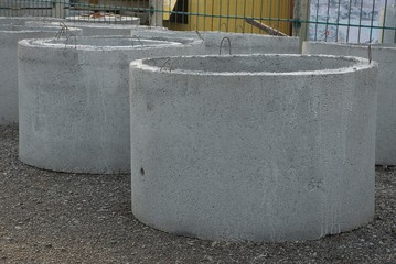 a row of industrial gray concrete rings stand outside