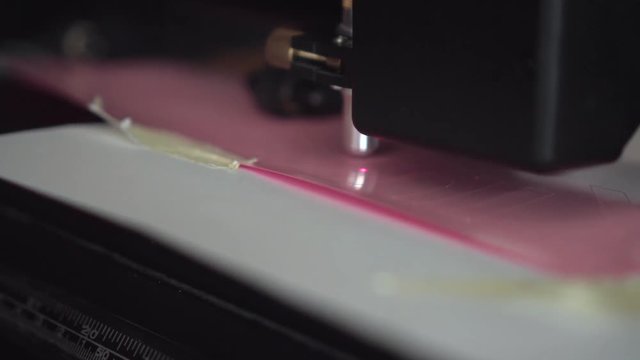 Cutting plotter. Plotter cuts pink vinyl, film. Laser cuts vinyl, film. Industrial equipment for cutting vinyl and film.