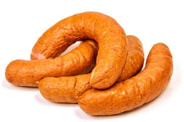 Grilled sausages with onions on a Board on a light background. Juicy sausage rings in a pile on a white background.