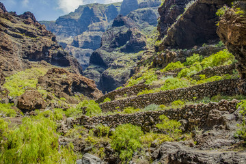 Rocks in the Masca gorge, Tenerife, showing solidified volcanic lava flow layers and arch formation. The ravine or barranco leads down to the ocean from a 900m altitude.