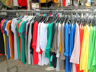 stand with many colored cotton t-shirts in the hangers