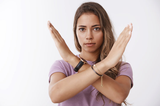 Serious-looking fed up woman decide finish inappropriate behaviour showing cross stop gesture frowing disapproval, saying no, forbid you, expressing dislike disagreement, standing white background
