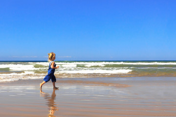 Fototapeta na wymiar The girl is walking along the beach on a sunny day.
