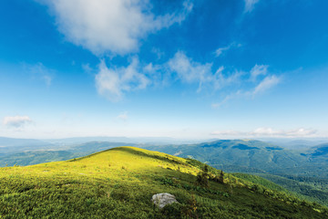 Fototapeta premium mountain landscape in dappled light. clouds on a blue sky above the green hill and distant ridges. fresh forenoon weather. vivid colors. summer travel and absolute freedom concept