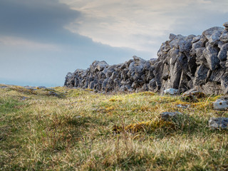 Dry stone fence in a field, Cloudy sky, Summer day. Burren, Ireland.
