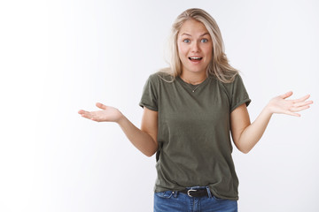 Fototapeta na wymiar Woman did not expect see friend in mall holding out hands sideways open mouth and raising brows in surprise and amazement being excited and confused posing questioned over white background