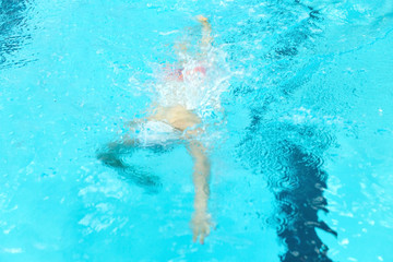 A young boy pounds in the pool.