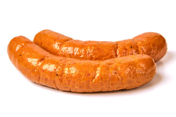 Grilled sausages with onions on a Board on a light background. Juicy sausage rings in a pile on a white background.