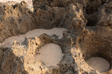Formação rochosa vista em detalhe. Detalhe de formações rochosas na praia que, formam buracos nos quais a areia fica retida.