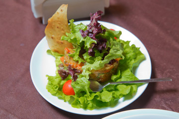 Fresh vegetable salad with tomatoes and lettuce . Fresh vegetable salad in plate . Vegetable salad with fresh lettuce, tomatoes and cucumber in clay pot . Closeup of vegetable salad .