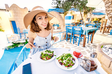 Young elegant girl in the restaurant seasoning salad with olive oil. Concept of Greek cuisine and...