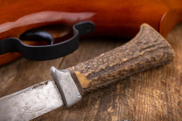 Old little dirty hunter's knife and firearm. Hunting accessories needed for hunting big game.