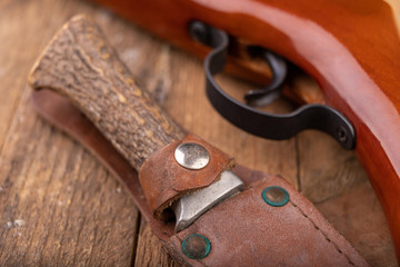 Old little dirty hunter's knife and firearm. Hunting accessories needed for hunting big game.