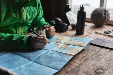Young man planning a journey with a pen and a map.