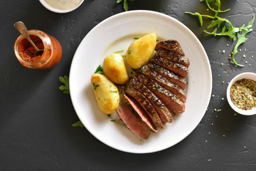 Sliced medium rare roast beef with potato