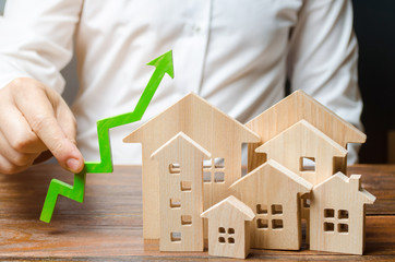 A man holds a green arrow up near a set of houses or a city. Growth indicators of the city, raising...